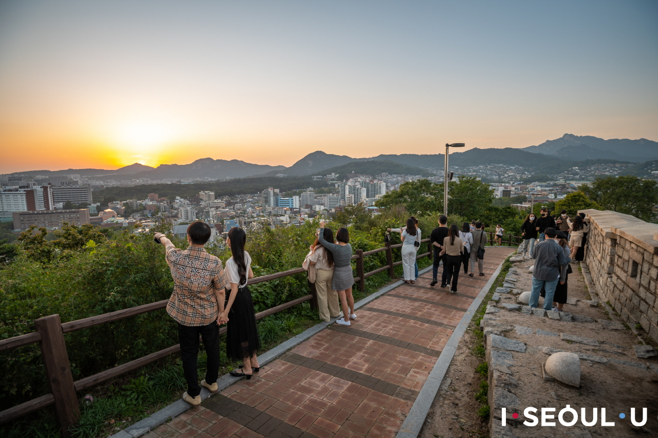 登上駱山公園頂，欣賞晚霞渲染首爾市景的人們