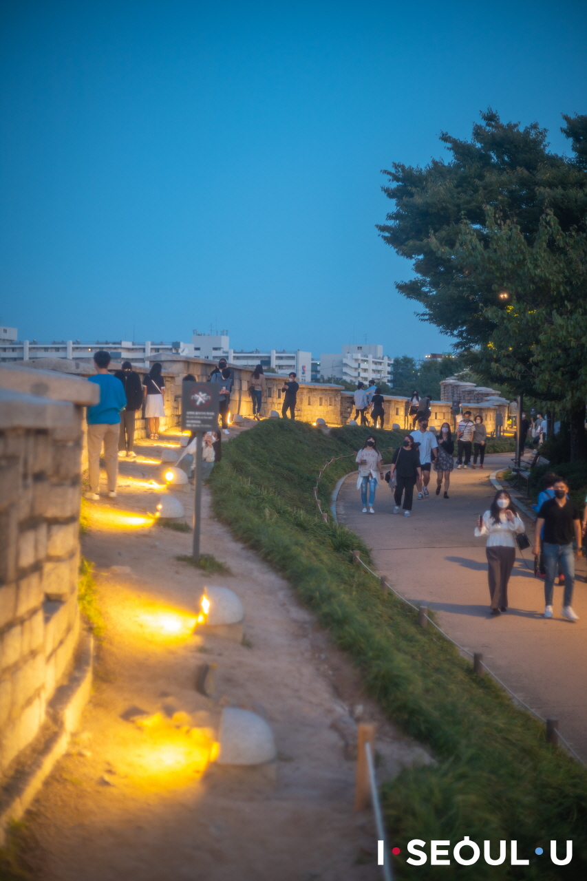 人們走在夜裡被燈點亮的駱山公園城郭路