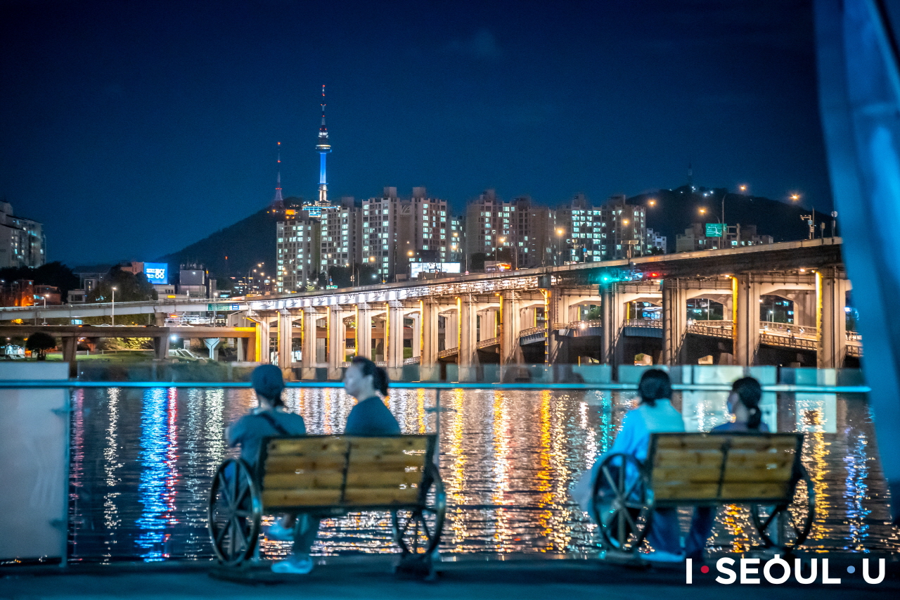 坐在三光島長椅上眺望漢江夜景的人們