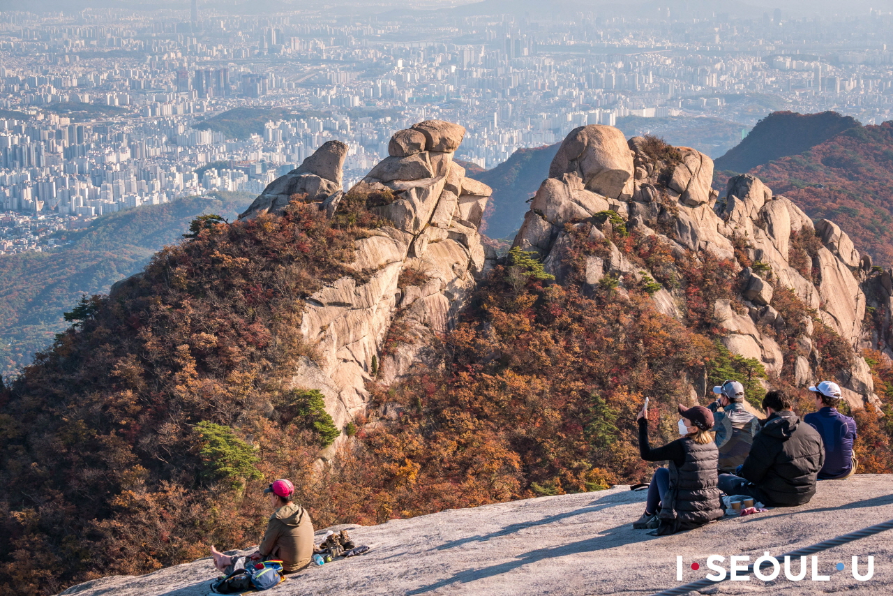 坐在北漢山頂上俯瞰首爾市區的人們