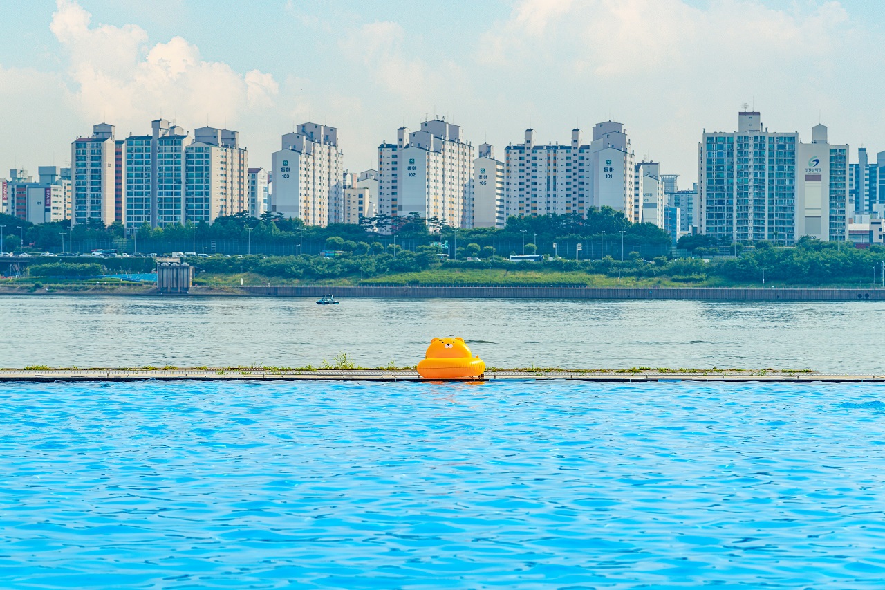 以小區爲背景，漂浮着黃色游泳圈的蘭芝漢江公園水上樂園的照片。